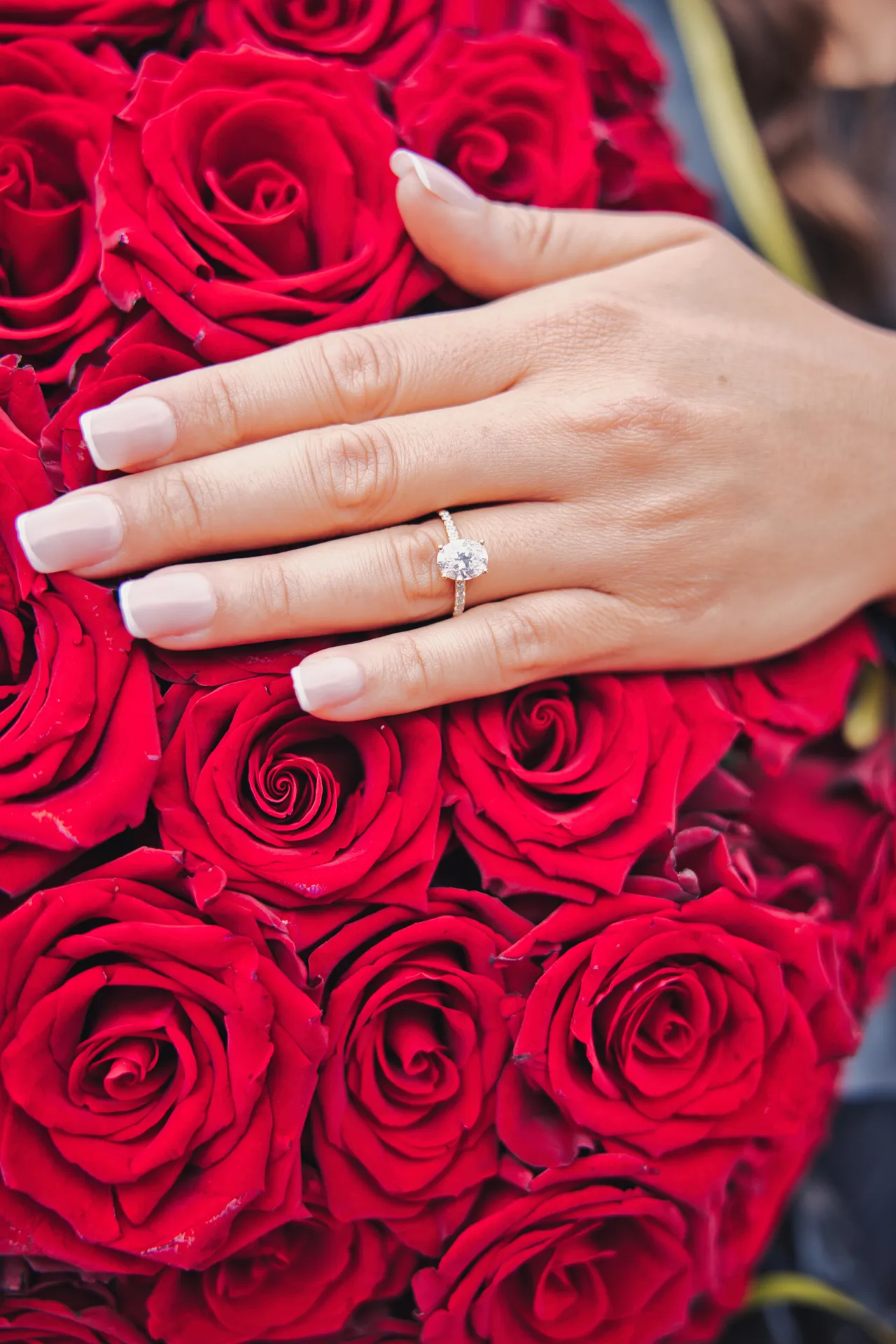 Detailaufnahme Verlobungsring auf einem Strauß roter Rosen