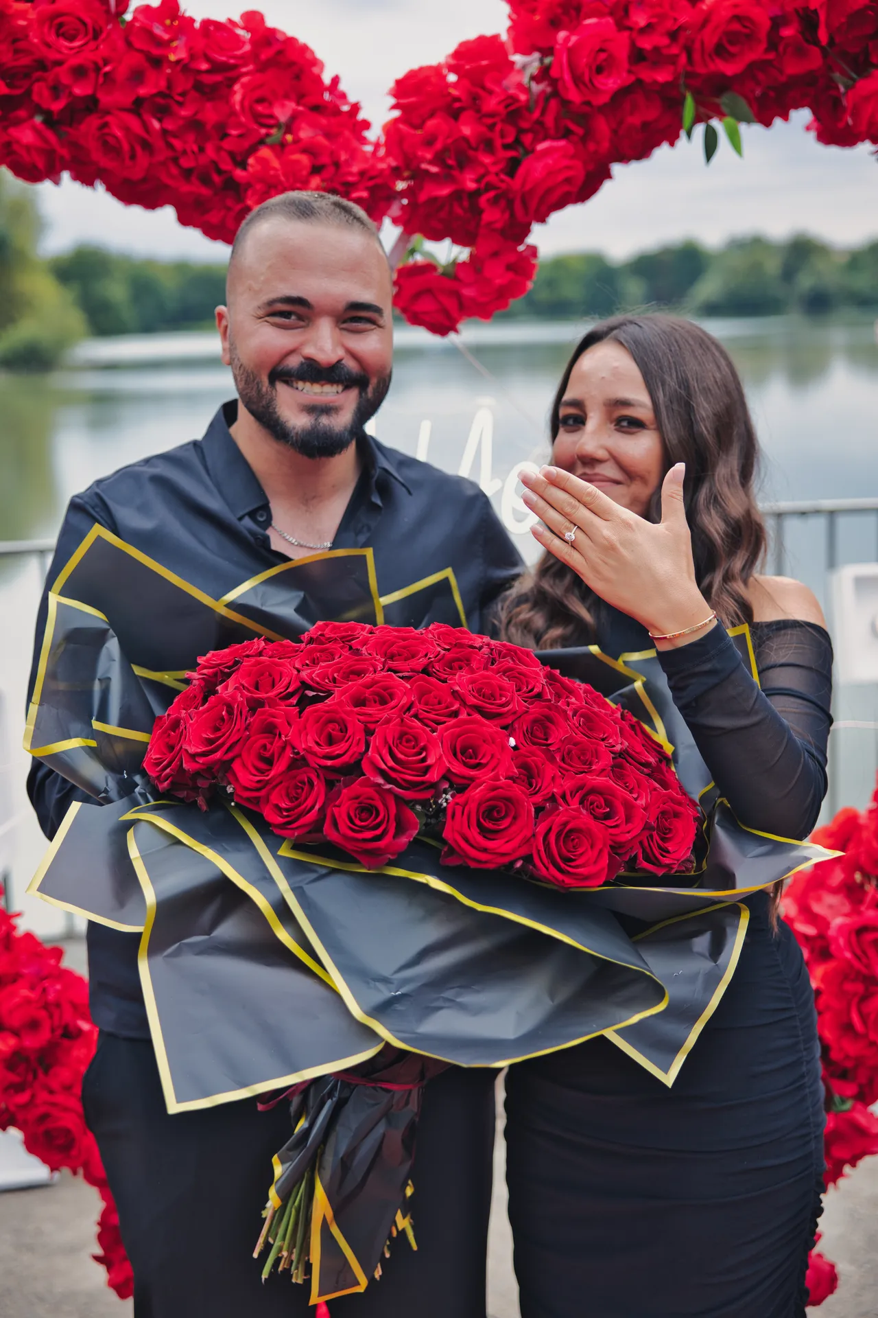 Paar nach dem Heiratsantrag am Berger See mit Rosenstrauß und Ring