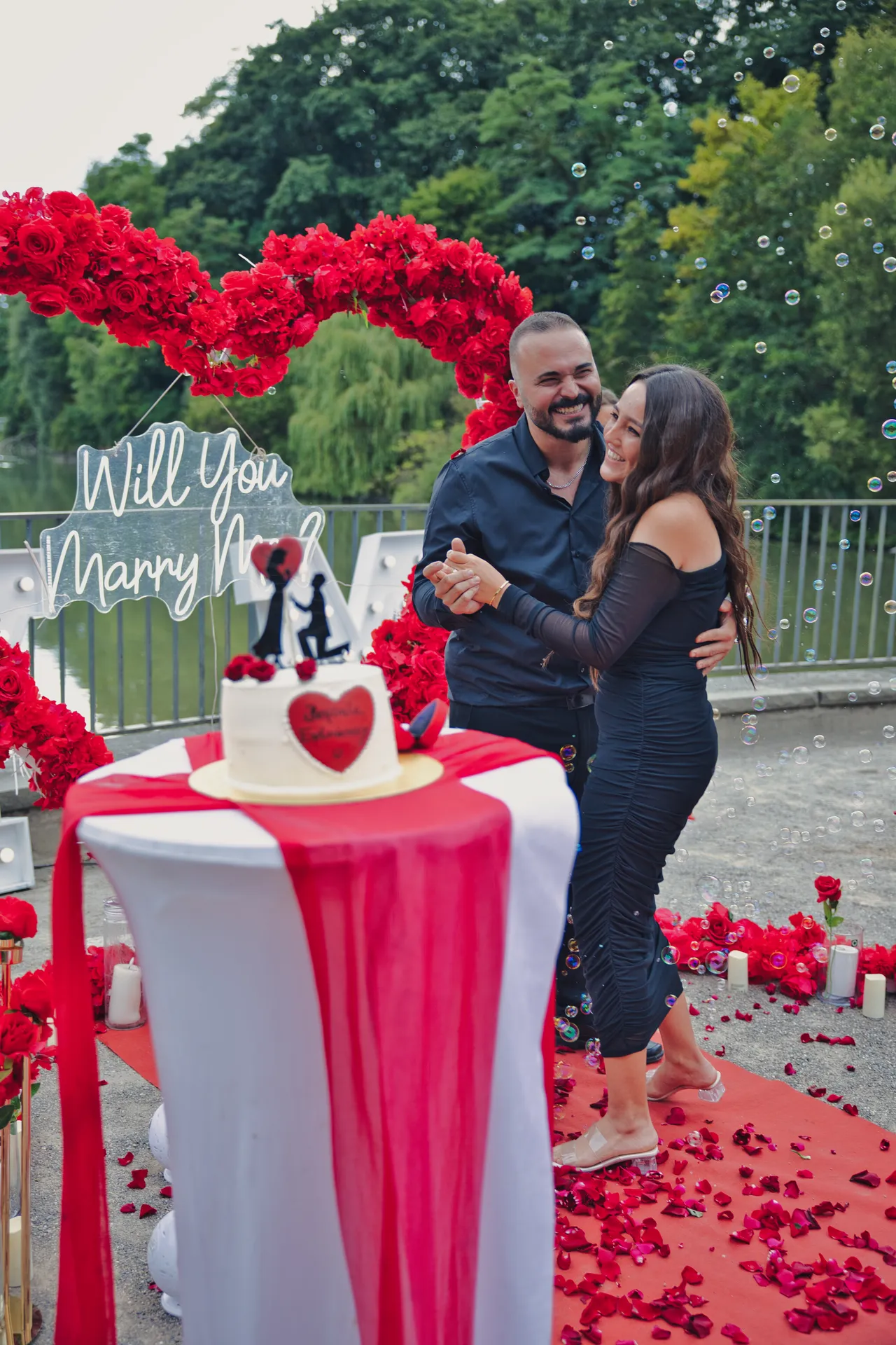 Paar tanzt nach dem Heiratsantrag vor Rosenherz und Torte am Berger See