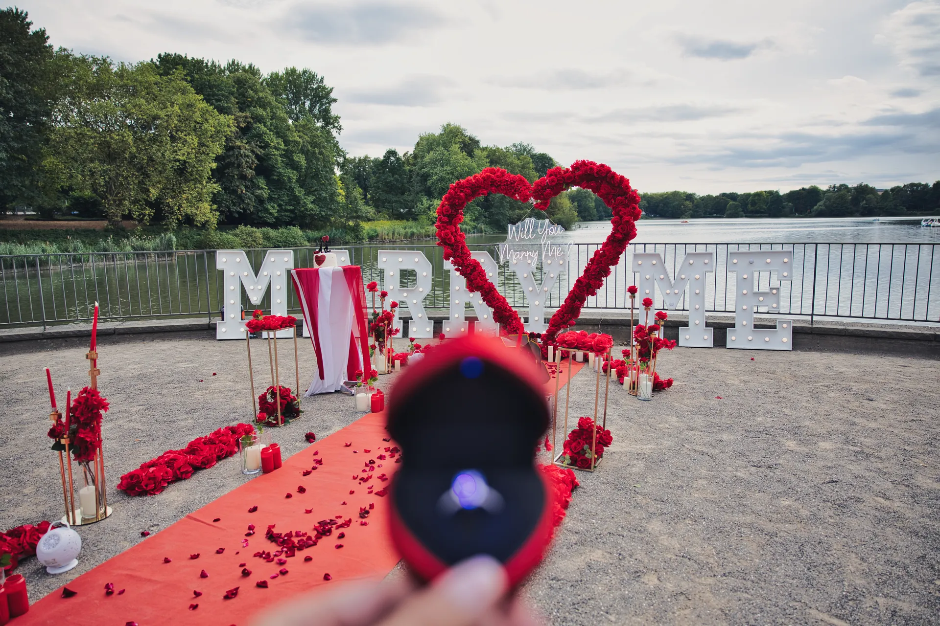 Ring im Vordergrund vor der romantischen Heiratsantrag-Dekoration am Berger See