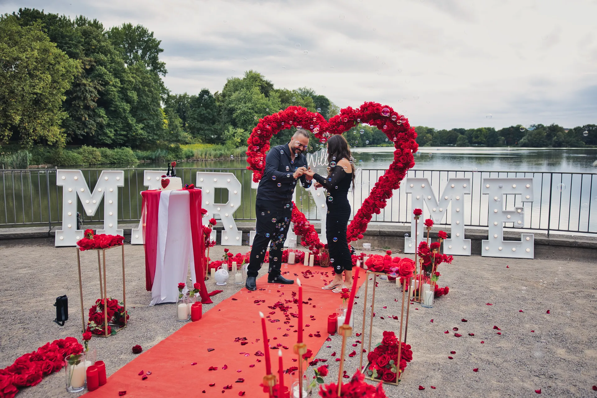 Heiratsantrag am Berger See: Ring wird angesteckt vor Rosenherz und MARRY ME Buchstaben